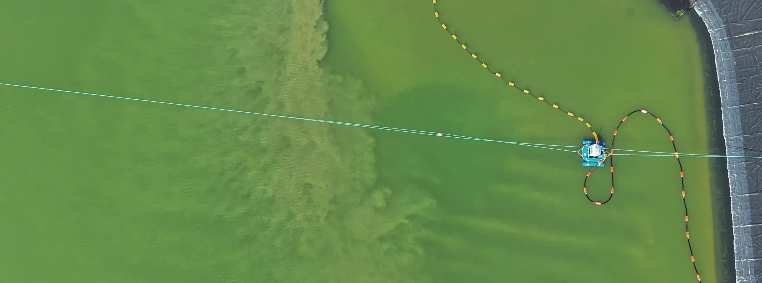Aerial view of desilting operations within a plastic lined process pond